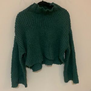Green mock neck sweater with cropped silhouette and bell sleeves.